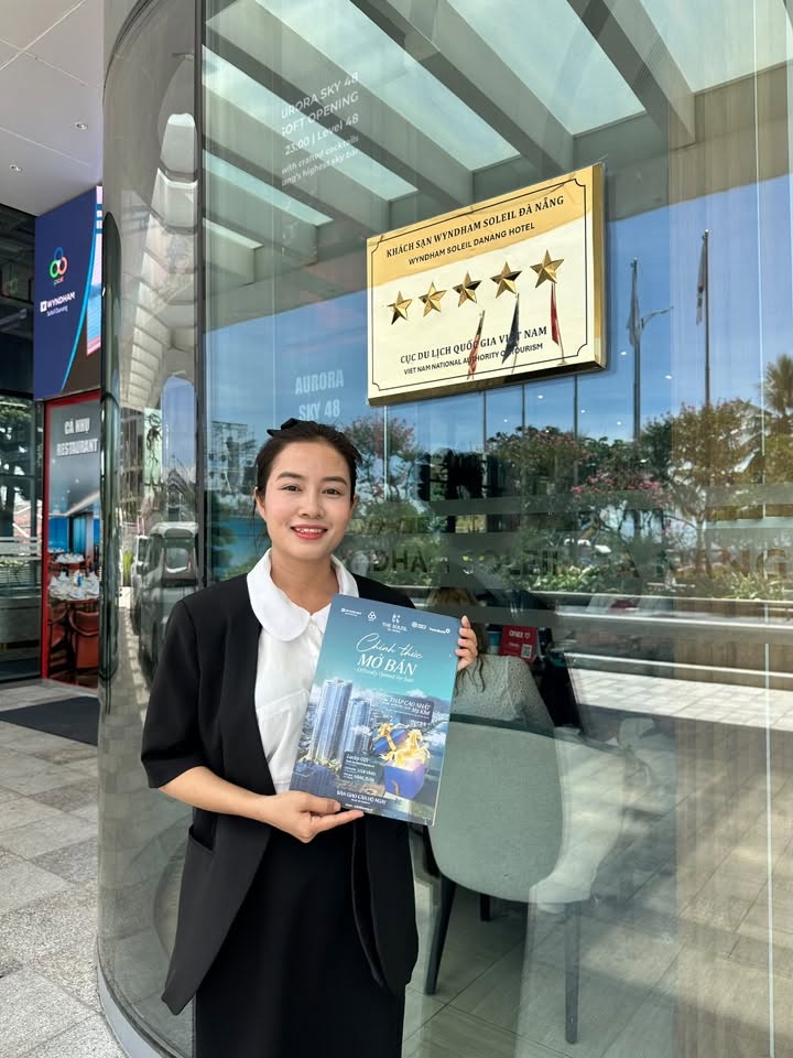 Đoàn Kim Nga đứng cạnh biển khách sạn Wyndham Soleil Danang 5 sao